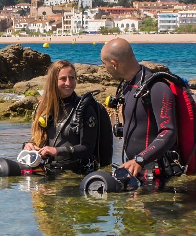 Zwei Taucher stehen im flachen Wasser mit ihrem Tauchequipment und halten je einen DiverTug Sport.