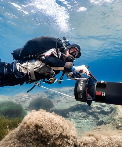 Taucher nutzt den DiverTug TEK24 Unterwasser Scooter über felsigem Meeresboden von DiverTug