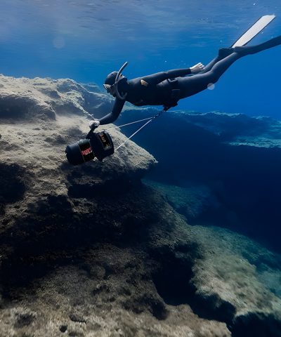 Freitaucher nutzt den DiverTug Sport nahe einer Felswand unter Wasser.