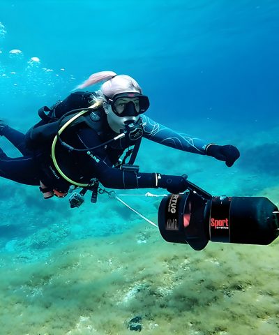 Taucherin nutzt den DiverTug Sport Unterwasser-Scooter während eines Tauchgangs über dem Meeresboden.